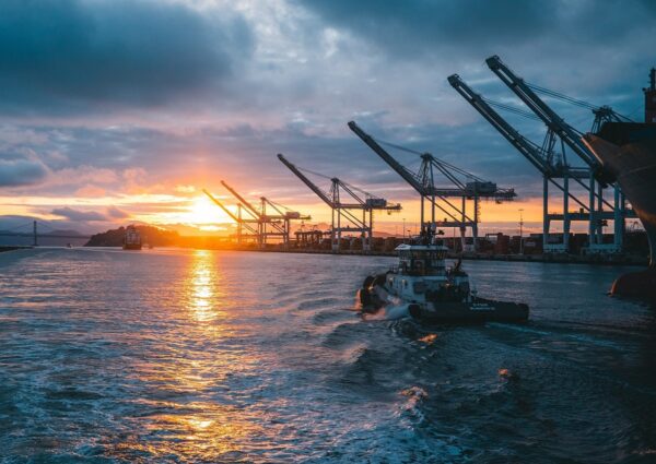 a panoramic shot of oil rigs at sea with a beautiful sunset in the background, under cloudy sky